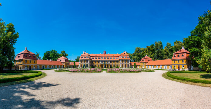 Panoramic view of Rajec Jestrebi Chateau on a sunny summer day with blue sky, blooming pink roses, and a fountain in front of the historical building.