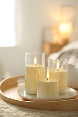 Beautiful LED candles on pouf indoors, closeup. Space for text