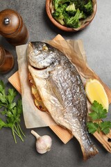 Tasty grilled fish, broccoli and spice on grey table, flat lay