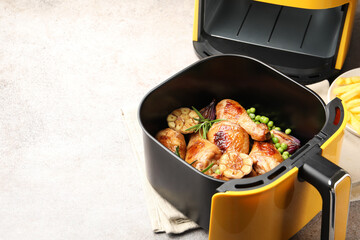 Air fryer basket with grilled chicken drumsticks, spices and green peas on grey table, closeup. Space for text