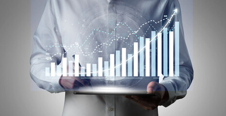 A person interacts with a digital tablet showcasing a growing graph and data visualization, symbolizing business growth, analytics, and modern finance strategies. Impute