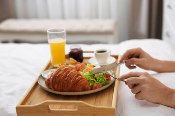 Man having delicious breakfast in bed, closeup. Hotel room service
