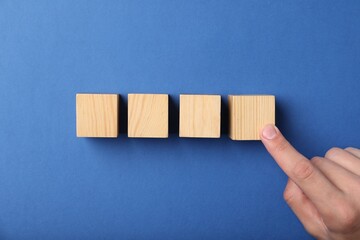 Man with wooden cubes on blue background, top view