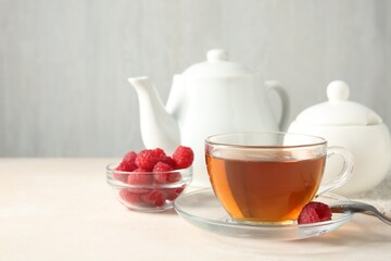 Delicious tea and raspberries served on white table. Space for text