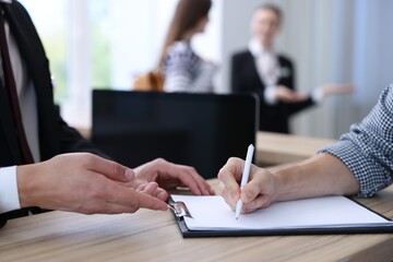 Receptionist working with guest at reception desk in hotel, closeup