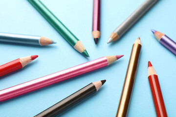 Colorful eye pencils on light blue background, closeup