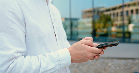 Close-up of man hands use phone. Male hands using texting mobile phone or chat. Outdoors