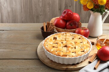 Delicious homemade pie, fresh apples, honey and flowers on wooden table, closeup. Space for text
