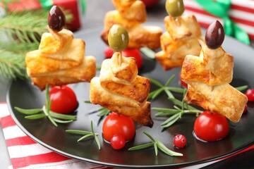 Tasty snacks with puff pastry, olives, tomatoes and rosemary on grey table, closeup. Christmas appetizer