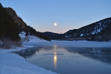 A frozen mountain lake shimmering under the full moon  