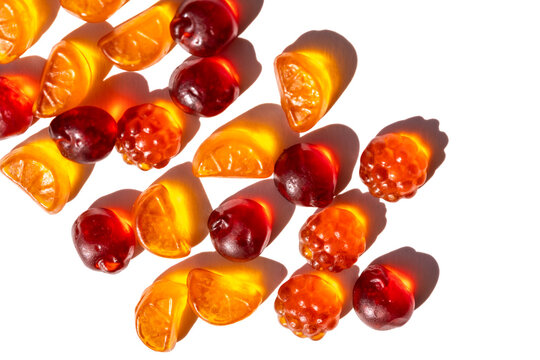 Flat lay of fruit gummies vitamins on bright white background, harsh sunlight and selective focus create strong shadows, minimalist snack composition for healthy eating concepts.