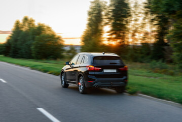 Fototapeta premium A black car is parked on the side of the road.