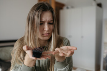 Healthy concept. woman holds up comb with long, fallen hair and looks at it.
