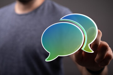 A person's hand interacting with two speech bubbles, representing online communication, digital connection, and networking