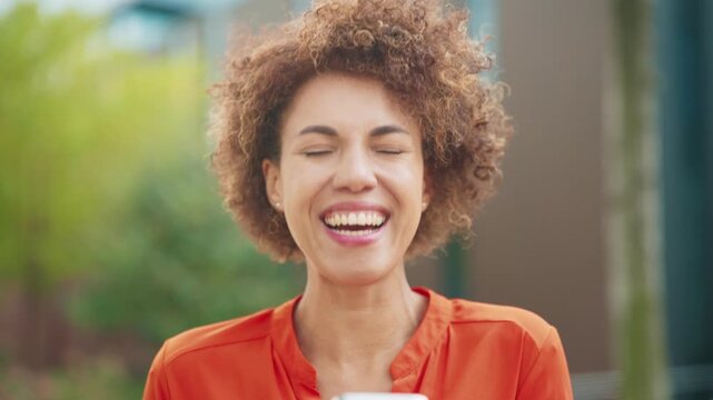 Excited African American woman outdoors looking directly at camera. Female smiling broadly with clenched fists exclaiming with joy and enthusiasm in bright daylight showing happiness and confidence.