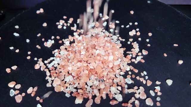 pink Himalayan salt falling on black slate background, close up, highlighting its natural texture and color, perfect for culinary and wellness uses, slow motion, rotation