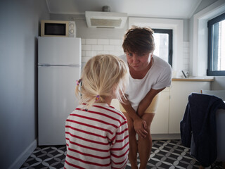Little girl begging for cookies in the kitchen while her mother gently says no to more sweets