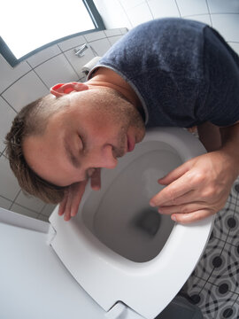Hungover man feeling sick by the toilet after a night of heavy drinking