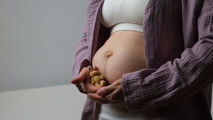 Women belly, pregnant woman hold cute baby rabbit near abdomen.