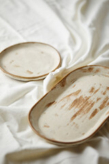 Ceramic plates on white textile background. Handmade ceramics.