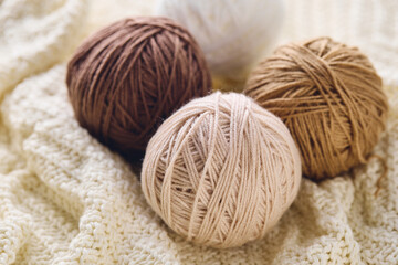 Balls of knitting yarns in natural colors on white knitted background, knitting, crocheting supplies.