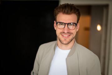 Headshot of a confident young man standing indoor and looking at camera