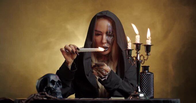 Witch dripping candle wax on tarot card during dark mystical ritual