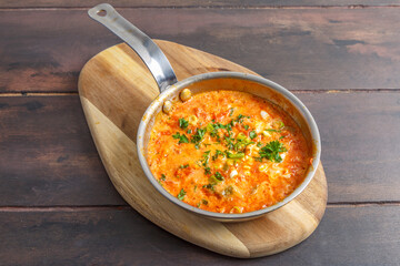 Menemen &ndash; &oelig;ufs brouill&eacute;s turcs aux tomates, poivrons et oignons, plat traditionnel de la cuisine turque, servi dans une po&ecirc;le sur table en bois. Petit-d&eacute;jeuner turc (Kahvaltı)