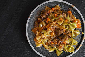 A plate of warm farfalle pasta salad with chicken livers, celery, and onions, a flat lay of a delicious French appetizer on a wooden table