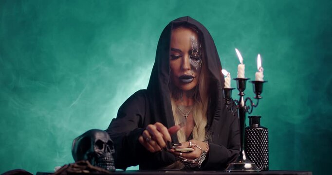 Witch laying out tarot cards on table in mystical teal smoke