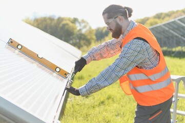 Worker installing solar panels using spirit level in solar power plant