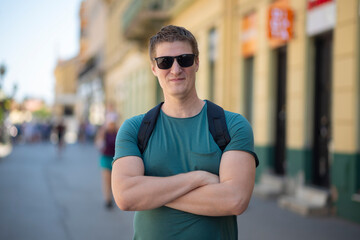 Man with sunglasses and backpack posing on city street