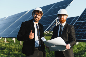 Engineers inspecting plans for solar panel installation in field