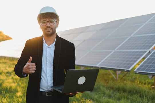 Arab businessman gesturing thumbs up while holding laptop near solar panels - Powered by Adobe