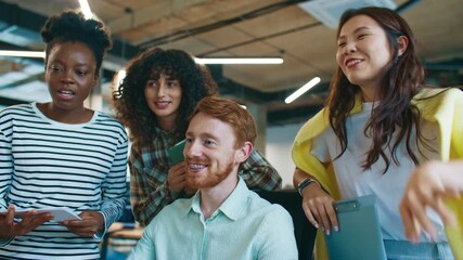 Focused man pointing at computer screen with pencil explaining task to coworkers standing nearby. Team listening and smiling during discussion. Office collaboration and learning process. - Powered by Adobe