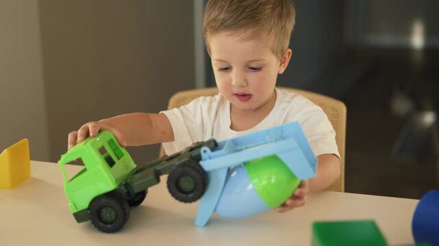 Toddler plays with toy truck and shape sorter on table indoor boy child show concentration and learning through play with colorful mixer truck promoting fine motor skill and imaginative play