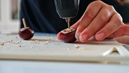 Caucasian Kid Drilling Hole in Chestnut Making Figurine for Autumn Decoration School Project