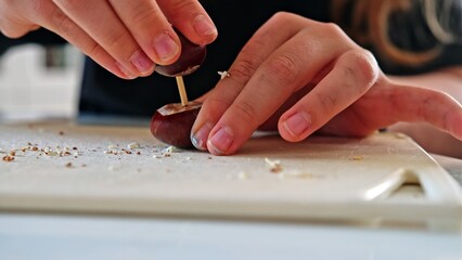 Caucasian Kid Drilling Hole in Chestnut Making Figurine for Autumn Decoration School Project