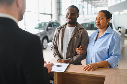 Couple buying new car in dealership talking with salesman - Powered by Adobe