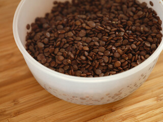 Cooked green lentils in a plastic bowl. Close up.