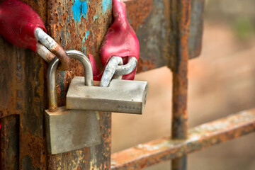 Old and rusty metal gate of a factory closed with padlock