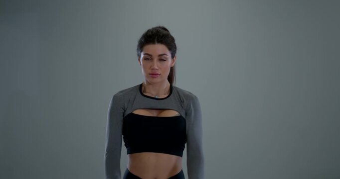 An athletic woman demonstrates arm circles in a spacious indoor setting. She is focused on her warm up routine showcasing her strength and dedication to fitness.