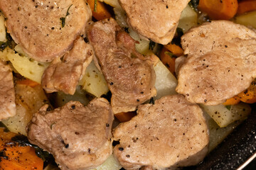 Roasted pork medallions with vegetables in a pan
