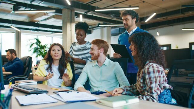 Focused coworkers discussing solution for computer problem at workplace. Men and women collaborating sharing ideas teamwork brainstorming to fix technical issue together in office setting.