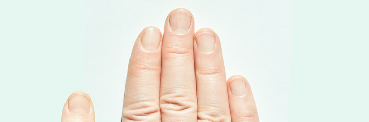 Close-up of caucasian adult female hand with manicured nails on light background.