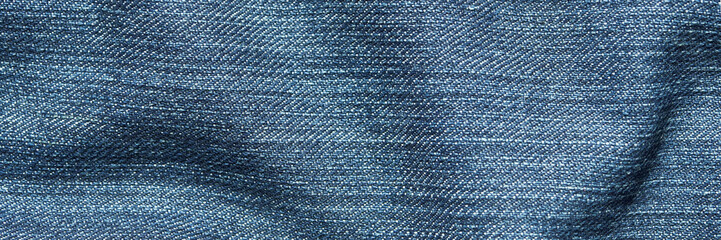 Close-up of blue denim fabric with detailed texture and woven pattern in soft light.