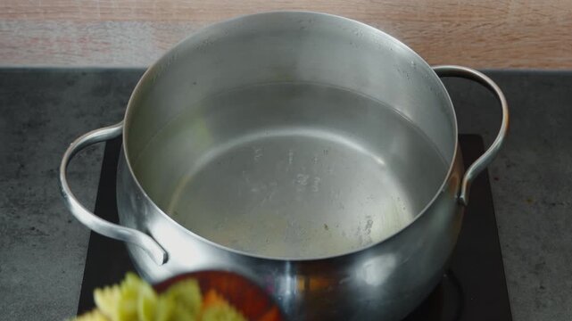 Add colorful farfalle pasta to salted boiling water to prepare a warm salad with chicken liver and celery