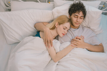 Happy young couple lying in bed under blanket, smiling and talking at night. Intimate romantic moment, cozy atmosphere, relationship bonding, bedtime, and night routine concept. couple, love, bed.