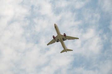 Airplane flying high in a cloudy sky during the day near an airport