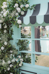 Close-up of Pastel Mint Window with Black and Mint Striped Awning Surrounded by White Roses and Baby's Breath